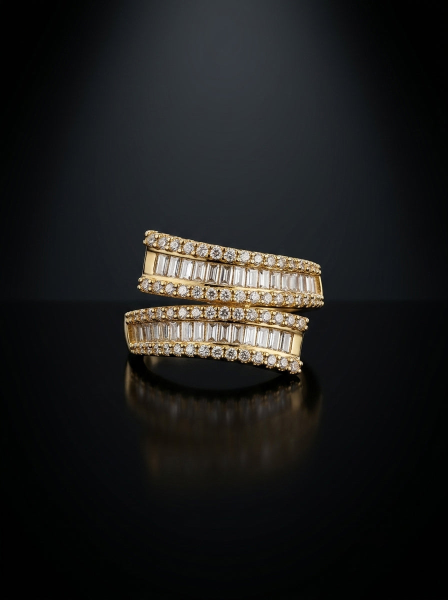 A pair of gold rings set with baguette-cut clear stones, displayed on a reflective black surface against a dark background.