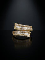 A pair of gold rings set with baguette-cut clear stones, displayed on a reflective black surface against a dark background.