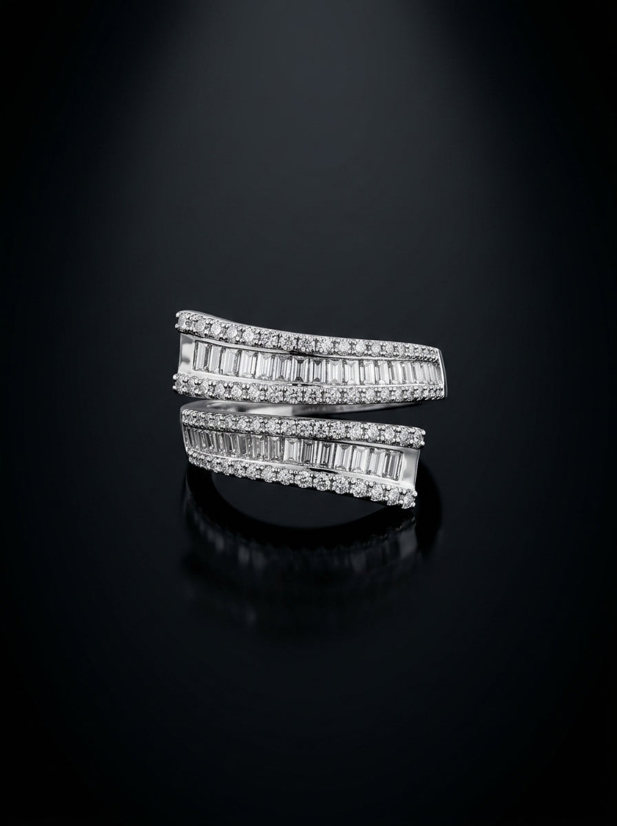 A silver-toned wrap ring set with baguette-cut diamonds, displayed on a reflective black surface against a dark background.