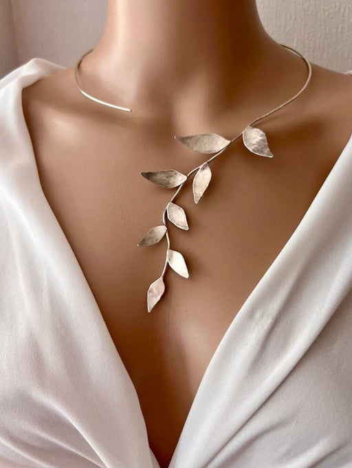 Silver leaf-shaped necklace on a mannequin with a white garment